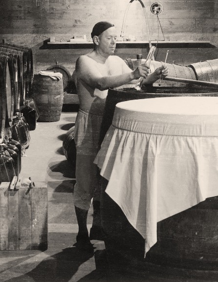 Vintage photo of Martin Ray sampling wine