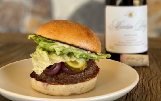Hamburger on plate with Martin Ray wine bottle in background